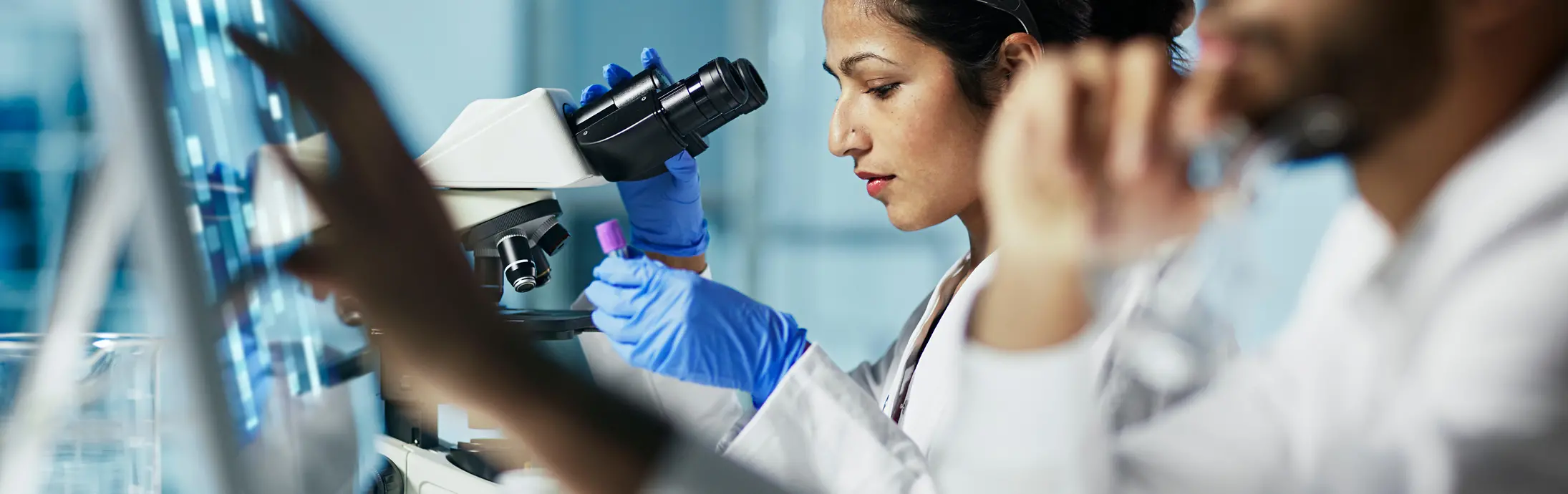 Una mujer sentada frente a un microscopio en un laboratiorio