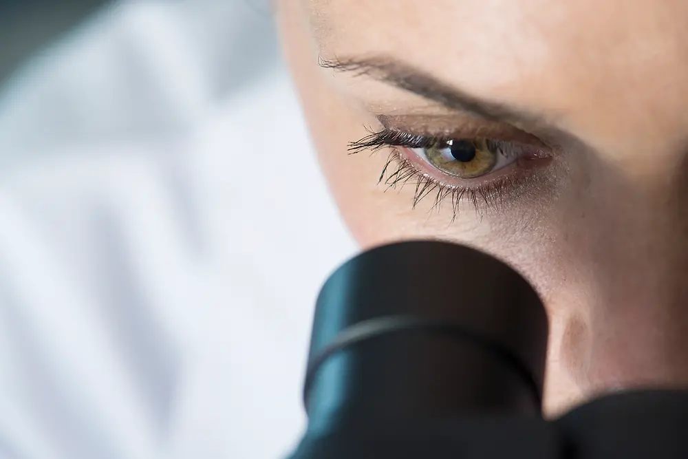 Ojo de una mujer viendo a través de un microscopio