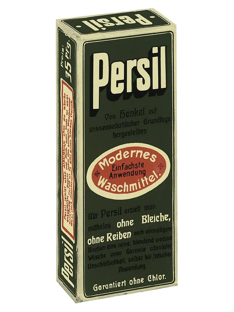 Caja vintage del detergente Persil con texto en alemán y etiqueta ovalada roja resaltando una aplicación moderna y sencilla.
