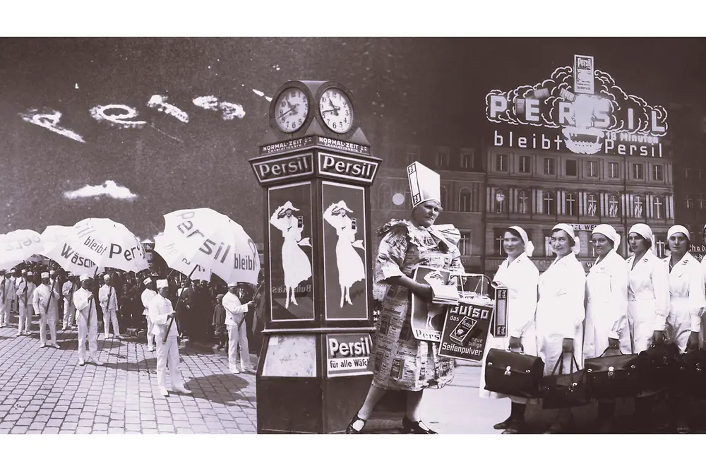 Collage de un anuncio vintage de Persil que muestra a personas sosteniendo paraguas de la marca, un reloj decorativo con carteles y un edificio con señalización iluminada al fondo.