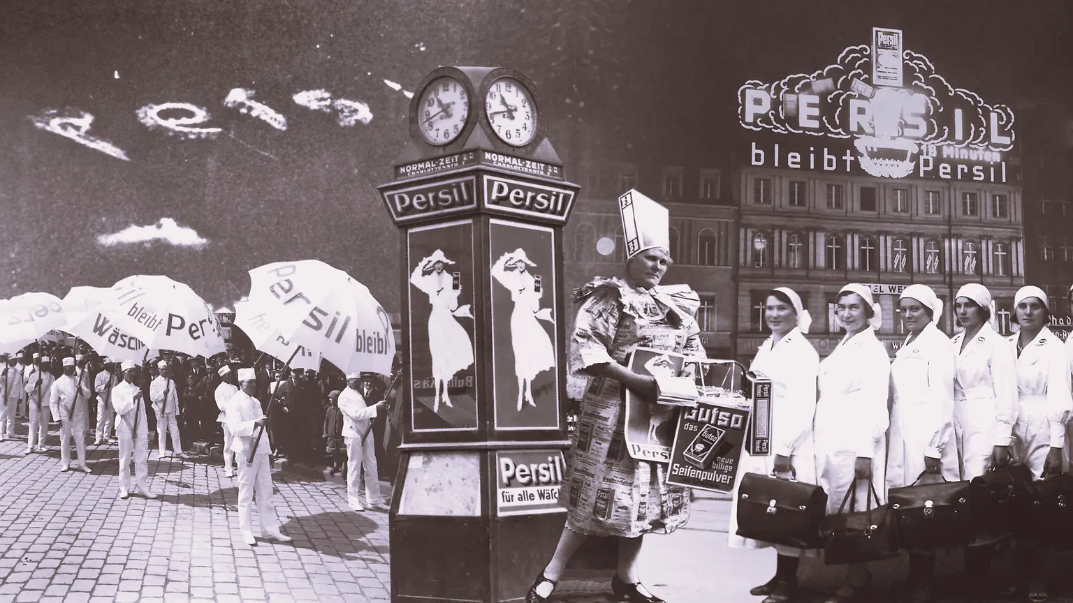 Collage de un anuncio vintage de Persil que muestra a personas sosteniendo paraguas de la marca, un reloj decorativo con carteles y un edificio con señalización iluminada al fondo.