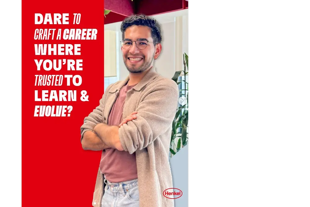 Una imagen que muestra a una persona de pie con los brazos cruzados en una oficina moderna. El diseño incluye un panel rojo intenso a la izquierda con texto blanco que dice: “¿SE ATREVE A CREAR UNA CARRERA EN LA QUE SE CONFÍE EN USTED PARA APRENDER Y EVOLUCIONAR?” La persona lleva una camisa rosa, un cárdigan beige claro y unos jeans de color claro. Aparece un logotipo de Henkel en la esquina inferior derecha.