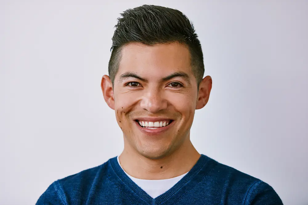 Retrato profesional de una persona que lleva un suéter azul sobre un fondo claro.